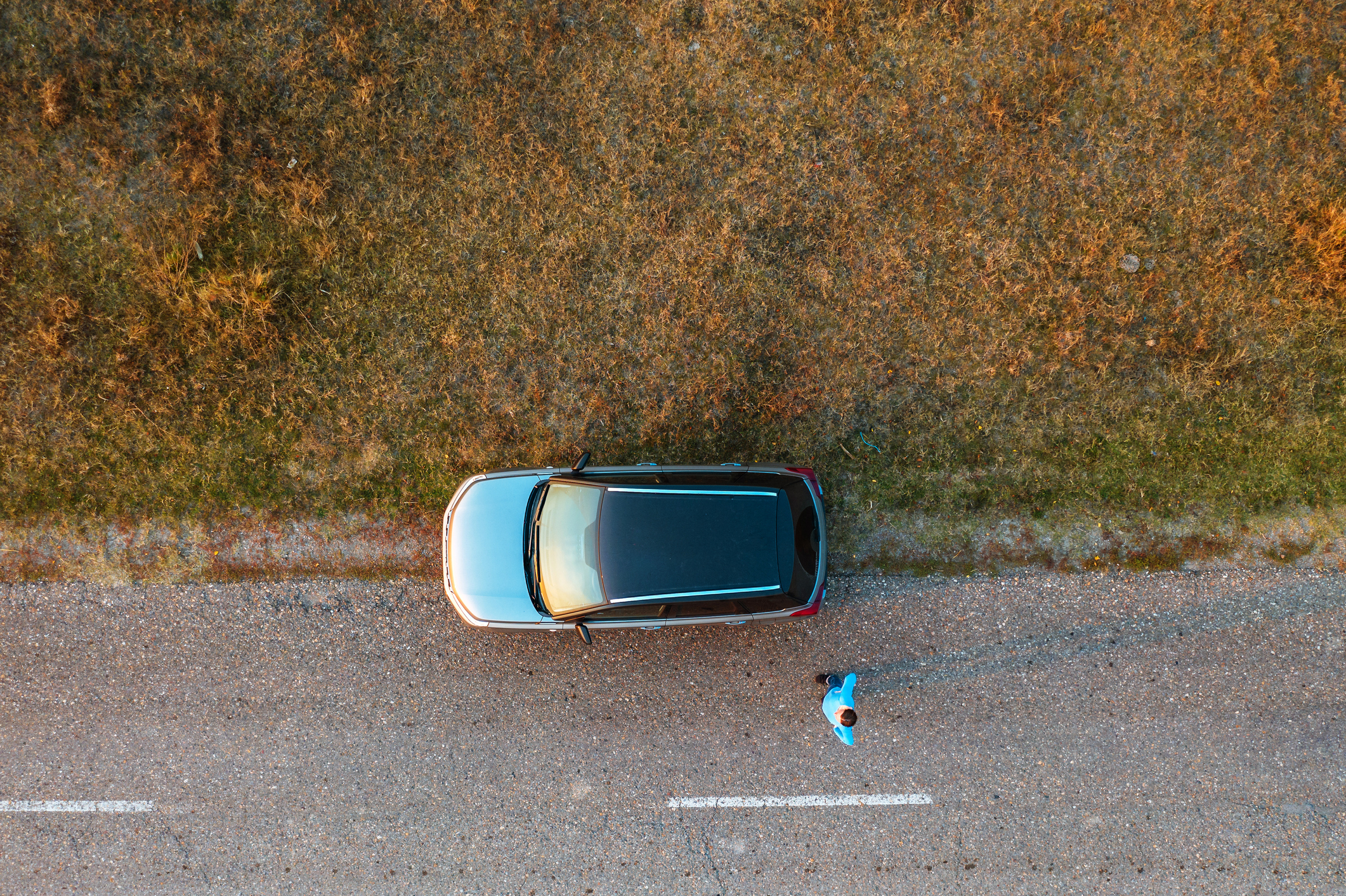 Woman And Car On Road Through Grassy Wastelands